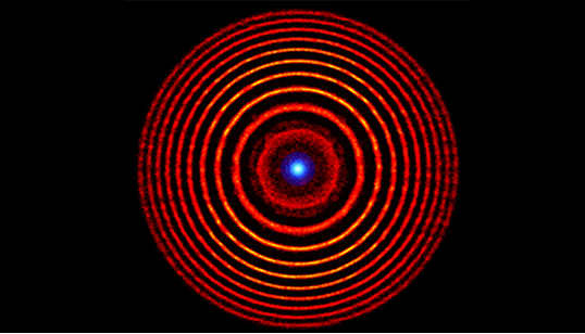 Colorized illustration from a simulation of a holographic plasma lens. The red concentric circles denote alternating high- and low-density plasma rings. The blue dot at the center represents the focused light. Image by Matthew Edwards/LLNL