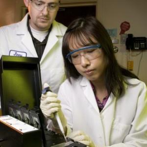 People in labcoats working with lab equipment