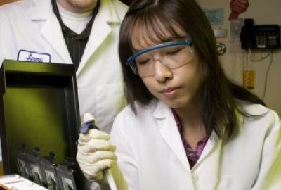 People in labcoats working with lab equipment